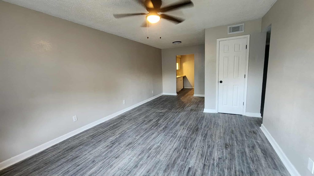A room with a ceiling fan and a door.