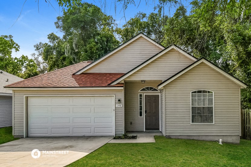 a tan house with a white garage door and a green lawn