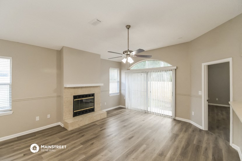 the living room with a fireplace and a ceiling fan