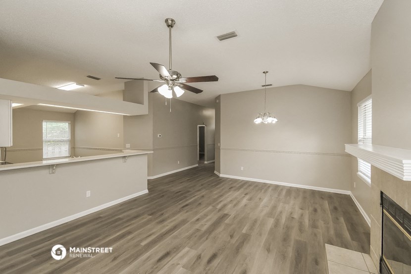 an empty living room and kitchen with a ceiling fan