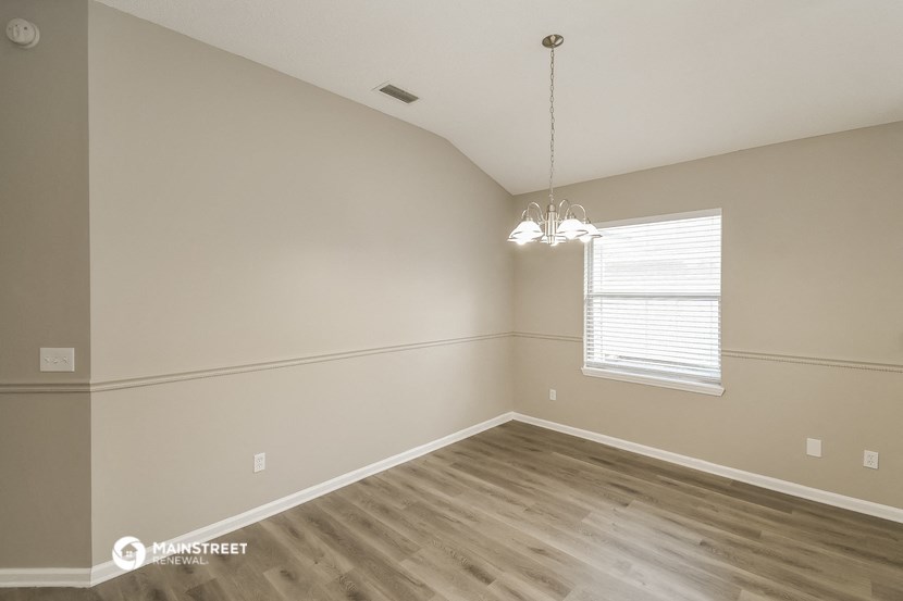 the spacious living room with wood flooring and a window