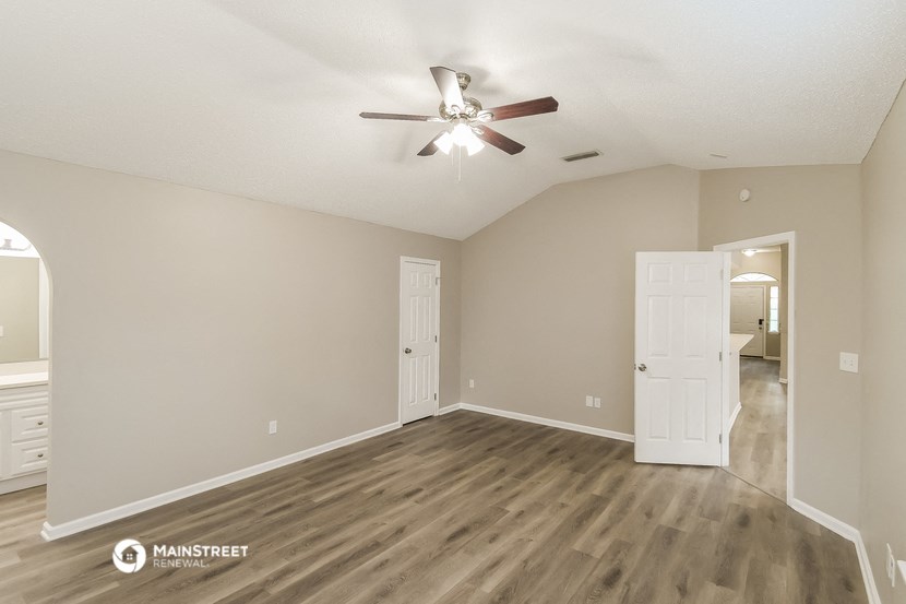 the spacious living room with hardwood flooring and a ceiling fan