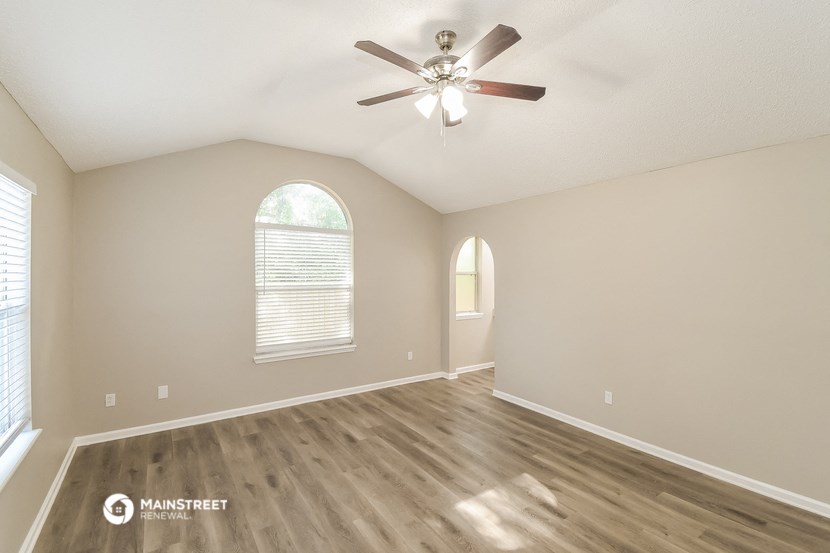 the spacious living room with hardwood floors and a ceiling fan