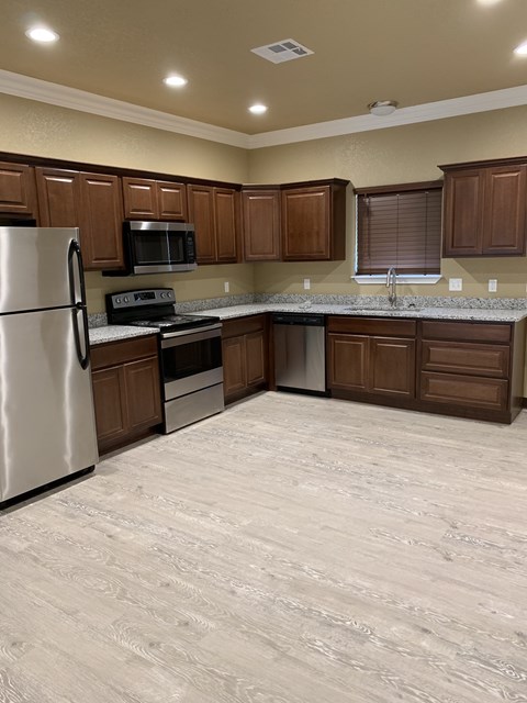 an empty kitchen with wooden cabinets and stainless steel appliances