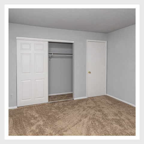 an empty bedroom with a closet and an open door