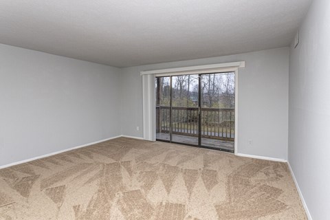 an empty living room with a sliding glass door to a balcony