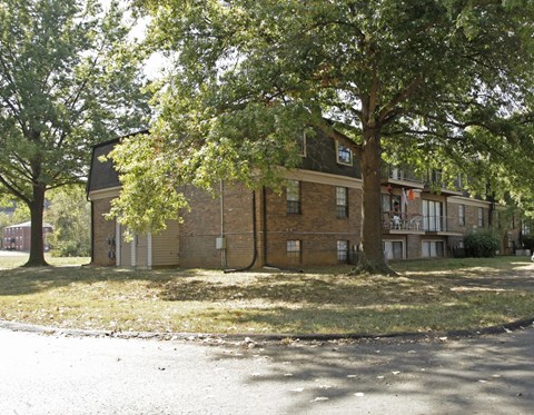 the exterior of a brick apartment building with trees