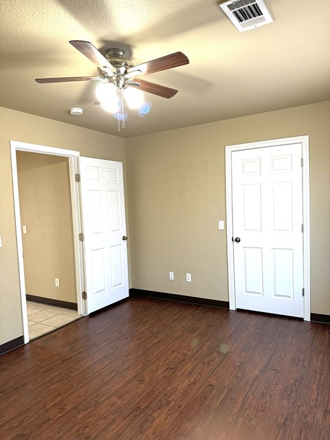 an empty living room with a ceiling fan and a closet