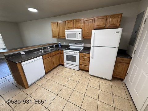 A kitchen with white appliances and wooden cabinets.