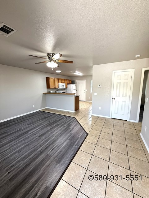 A room with a ceiling fan and a kitchenette.