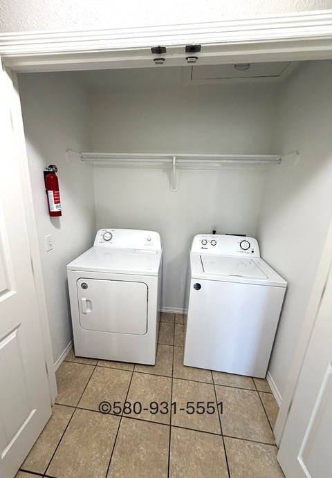 A laundry room with two washers and a fire extinguisher.