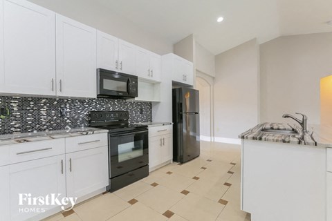 a white kitchen with black appliances and white cabinets