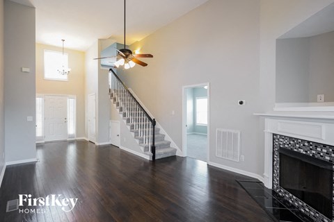 A spacious living room with a fireplace and a staircase.