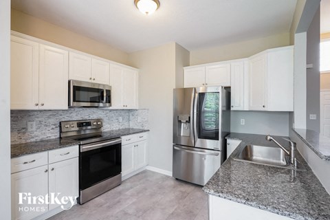 A kitchen with a stainless steel refrigerator and microwave oven.