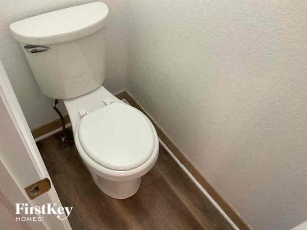 a white toilet in a bathroom with a wooden floor