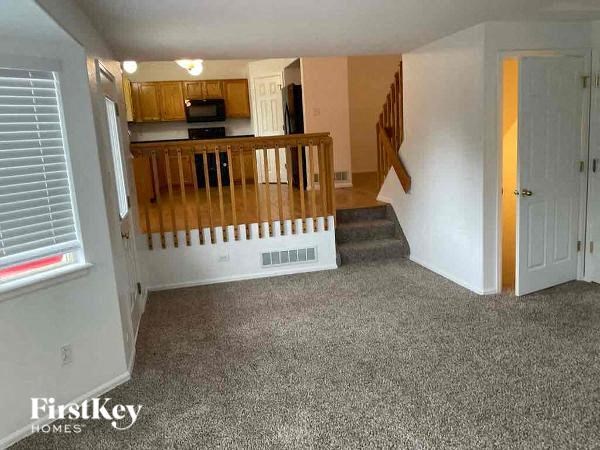 an empty living room with a staircase and a kitchen
