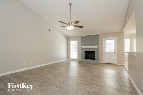 the spacious living room with fireplace and ceiling fan