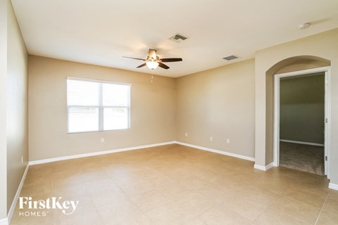 an empty living room with a ceiling fan and a door to a closet
