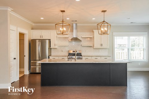 A kitchen with a black counter top and a stainless steel refrigerator.