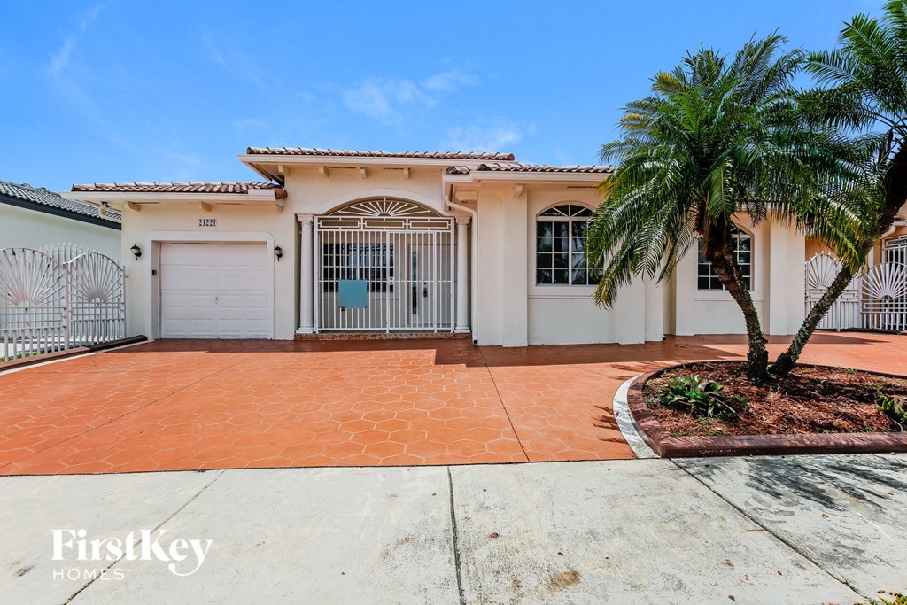 a house with a driveway and palm trees in front of it