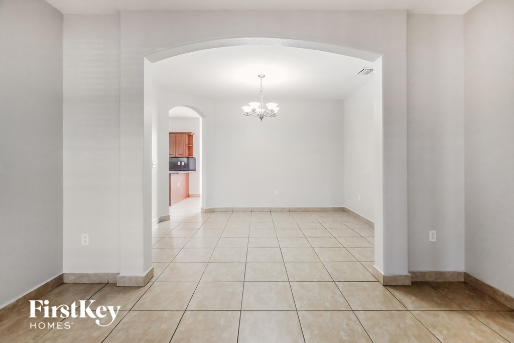 an empty living room with white walls and a tiled floor