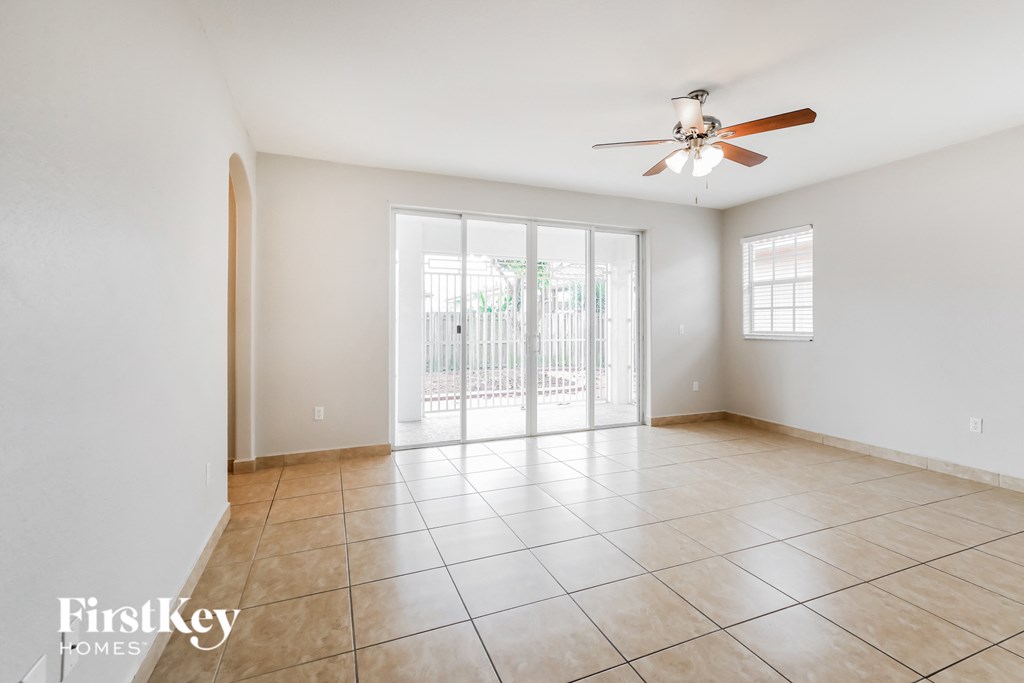 an empty living room with a ceiling fan and a sliding glass door