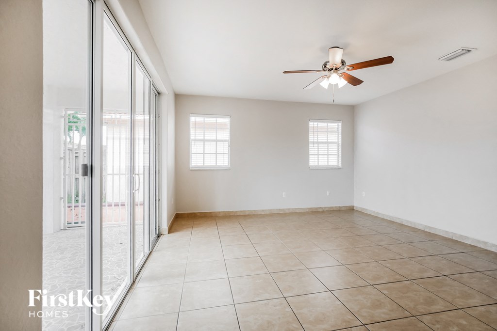 an empty living room with a ceiling fan and tiled floors