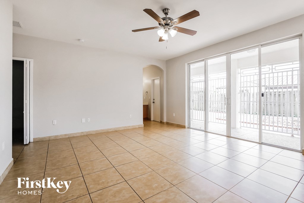 an empty living room with sliding glass doors and a ceiling fan
