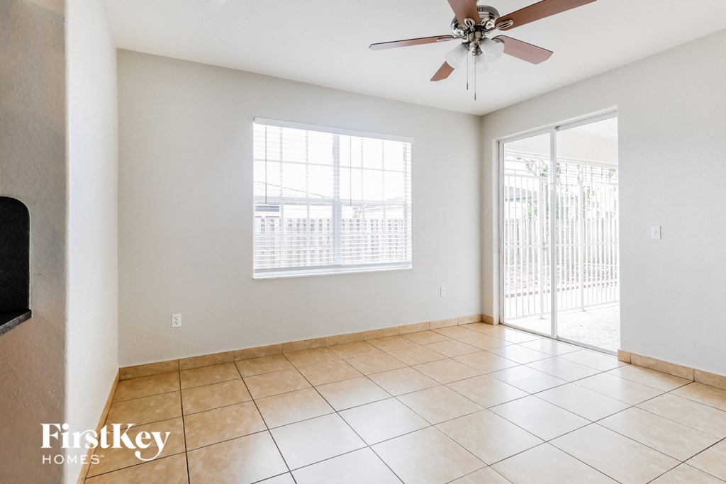 an empty living room with a ceiling fan and a sliding glass door