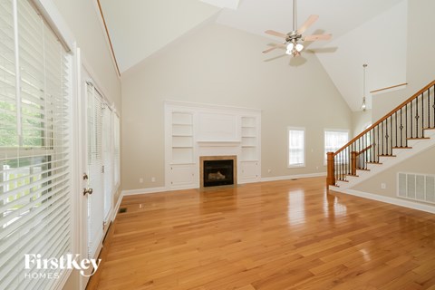A spacious living room with a fireplace and hardwood floors.