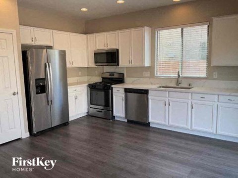 A kitchen with a refrigerator, microwave, oven, and sink.