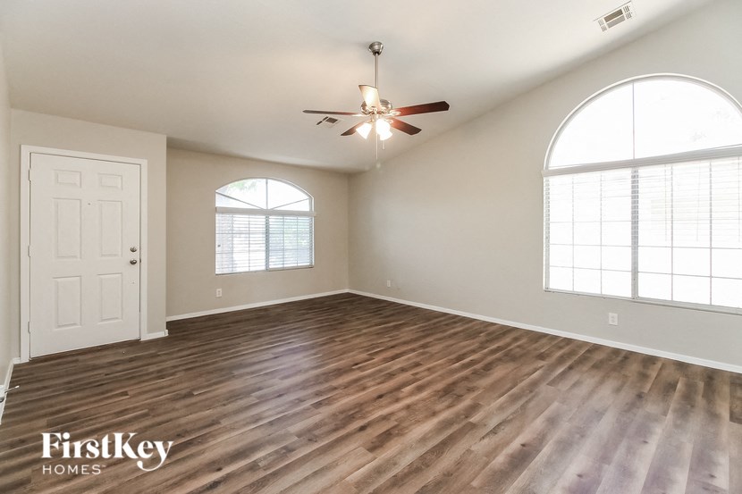 an empty living room with wood floors and a ceiling fan
