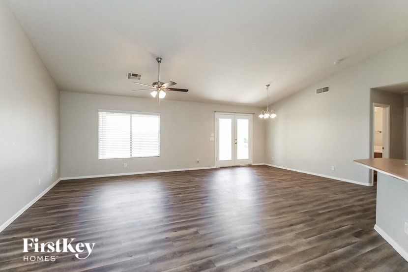 an empty living room with wood flooring and a ceiling fan