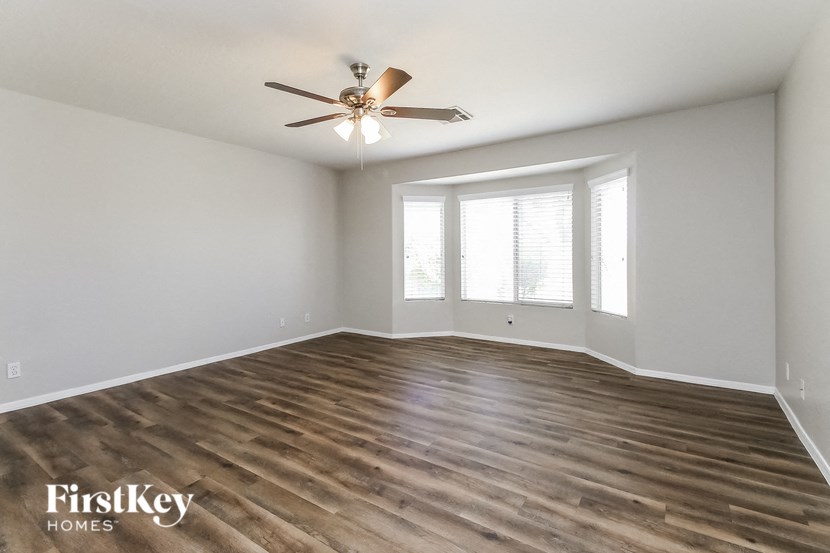 the spacious living room with hardwood flooring and a ceiling fan