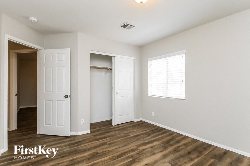 a bedroom with white walls and wooden floors and a closet