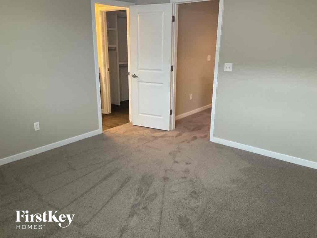 an empty living room with gray carpet and a white door