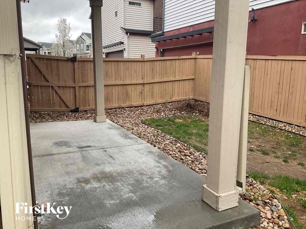 a backyard with a wooden fence and a concrete sidewalk