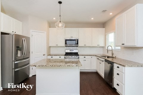 A kitchen with white cabinets and a granite countertop.