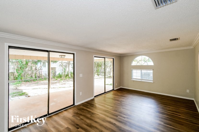 A spacious room with wooden floors and a large window.