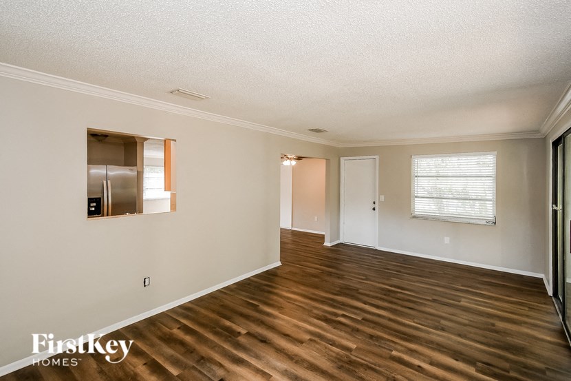 A room with wooden floors and a window with blinds.