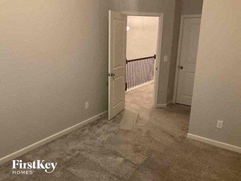 an empty room with a hallway and a door to a bedroom