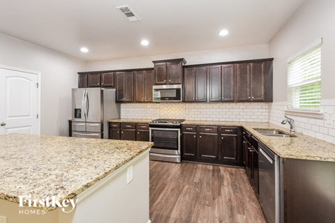 a kitchen with dark wood cabinets and granite counter tops and a sink