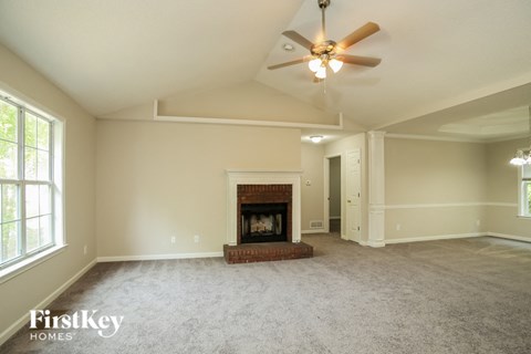A spacious living room with a fireplace and a ceiling fan.