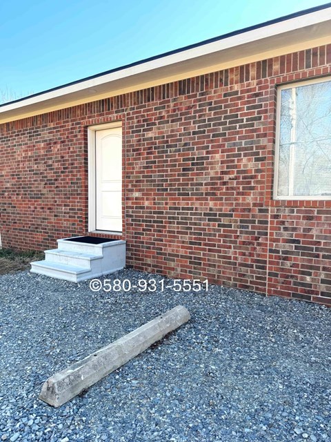 A red brick house with a white door and a small porch.