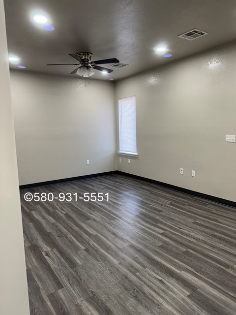 A room with a ceiling fan and wooden flooring.