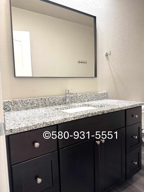 A bathroom with a sink, mirror, and cabinets.