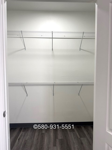 Empty white closet with shelves and a door.