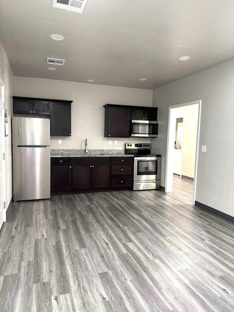 A kitchen with a stainless steel refrigerator, microwave, oven, and cabinets.