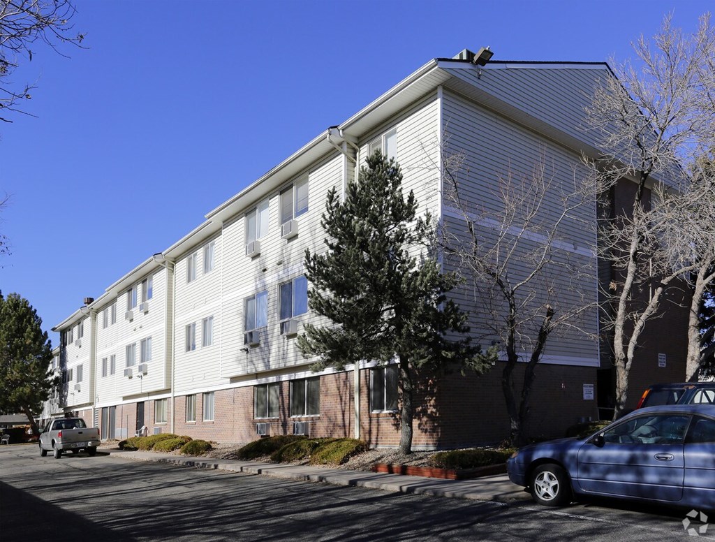 A blue car is parked in front of a white building.