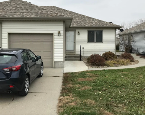 A black car is parked in front of a house.
